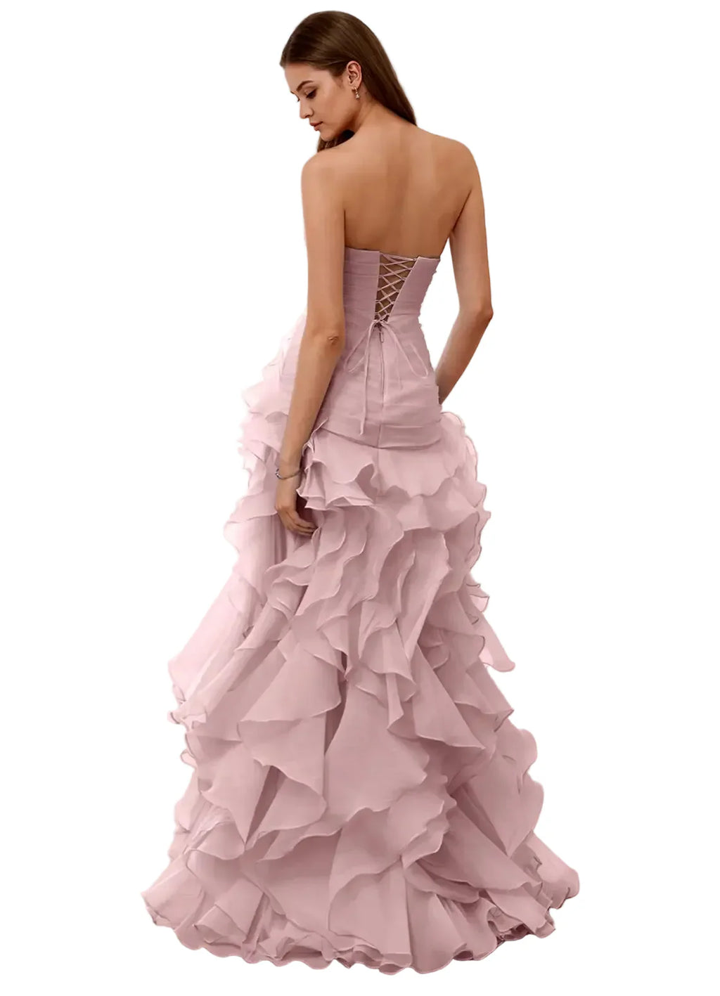 Woman wearing a pink strapless gown with ruffled layers in a room with white walls and wooden floor.