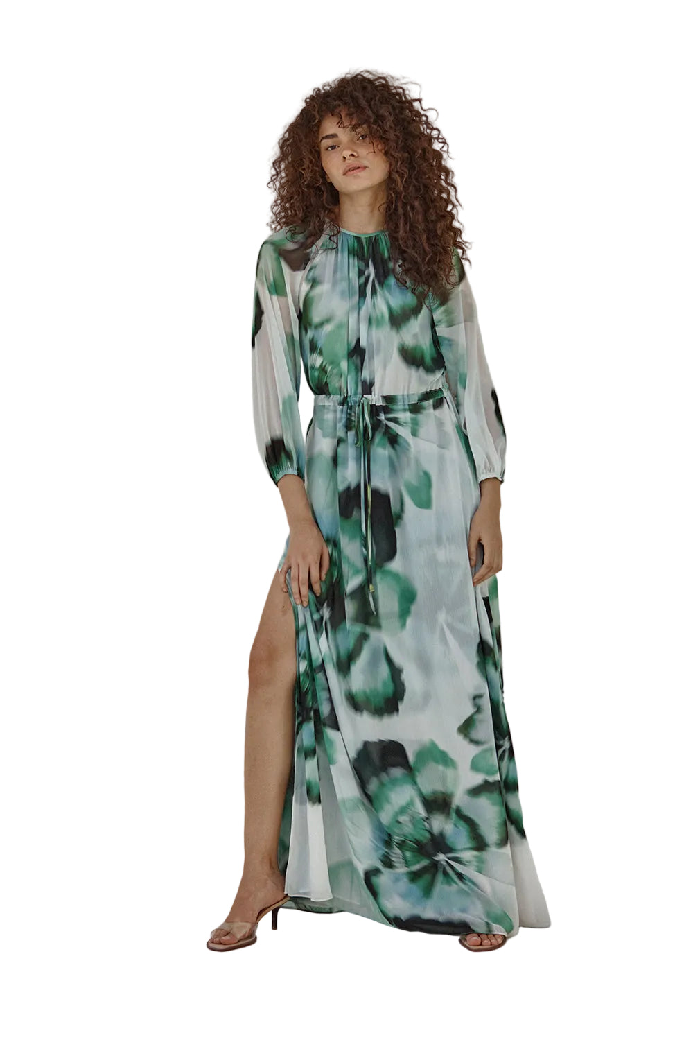 Woman wearing a floral dress with a slit, standing against a plain background
